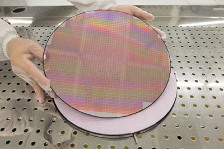 An iridescent wafer held over a grinding chuck